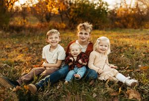 Children sitting together in a grassy field during golden hour sunset.