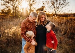 Family portrait session in a golden field at sunset with warm autumn lighting and natural poses.