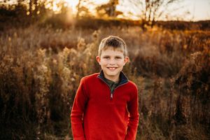 Candid outdoor portraits of children in red and brown sweaters at sunset.