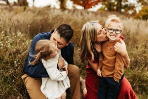 A candid family photo session in a rustic field with warm fall colors and natural lighting.