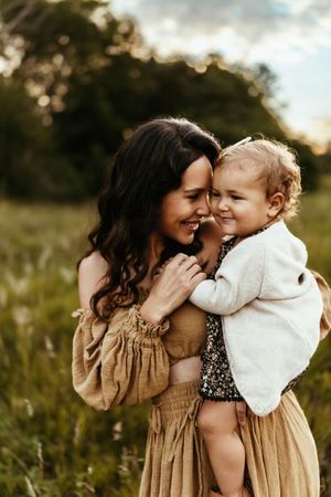 A tender moment between parent and child in a sun-drenched meadow at golden hour.