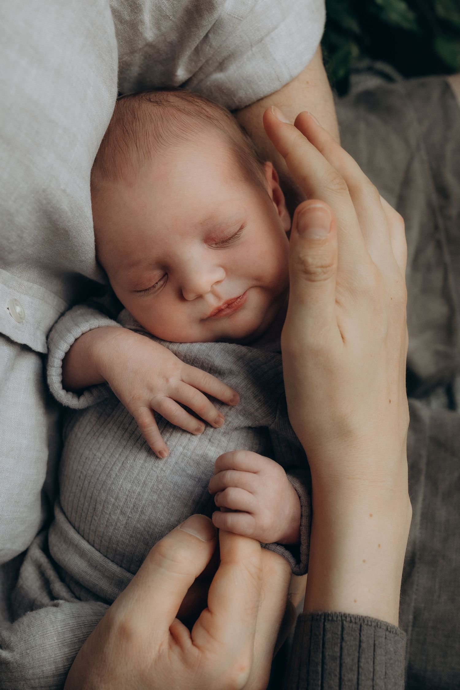 A baby girl smiling in her parent's arms, kent lifestyle at home new born photographer