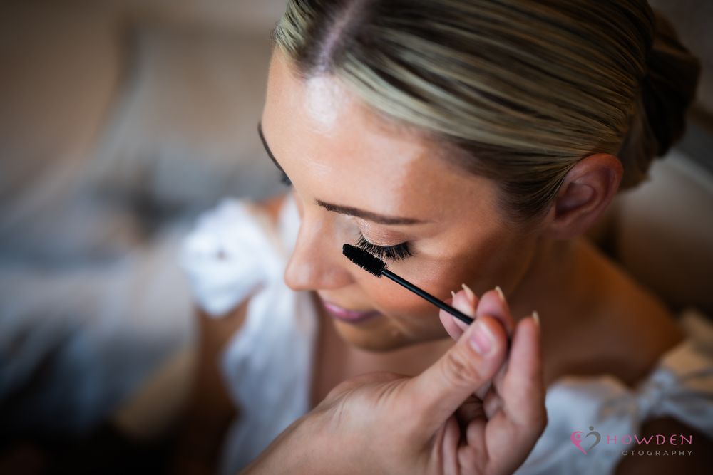 Applying mascara with a black mascara wand in a close up beauty shot.