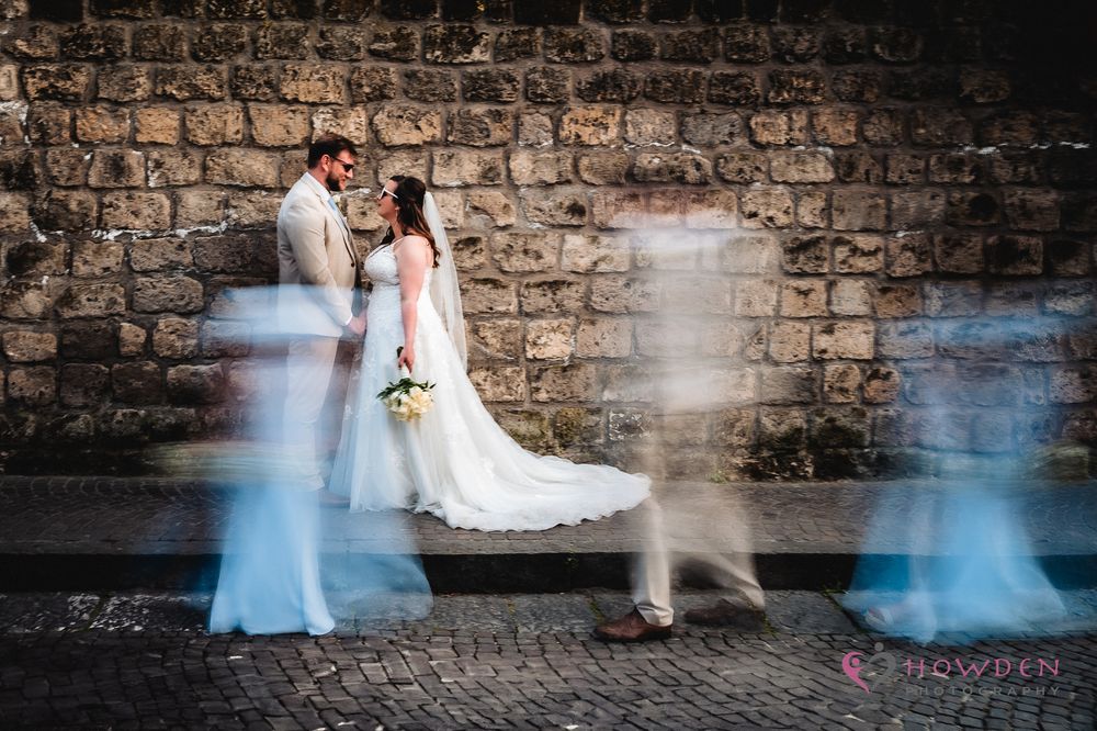 Long exposure photo showing motion blur of people dancing against a rustic brick wall background.