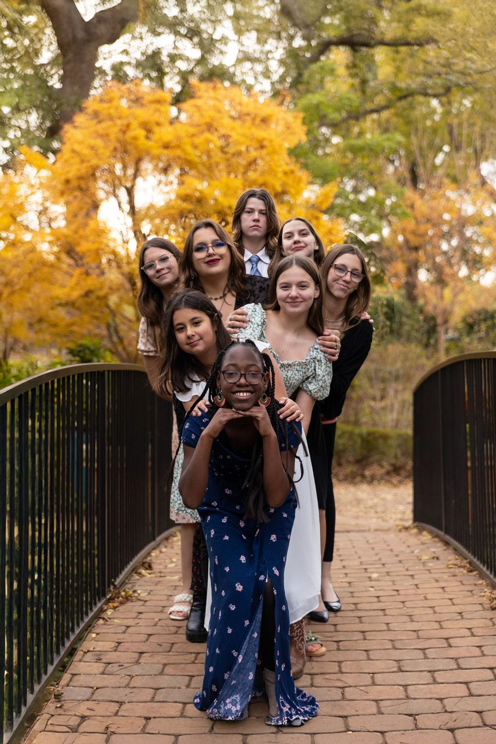 A group of young women pose on a bridge.
