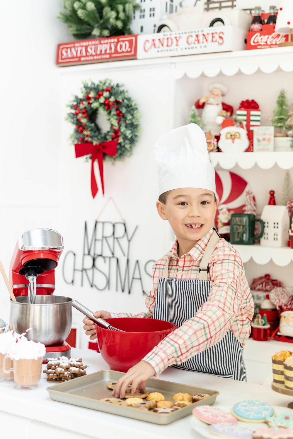 A young boy poses on a Christmas baking studio set.