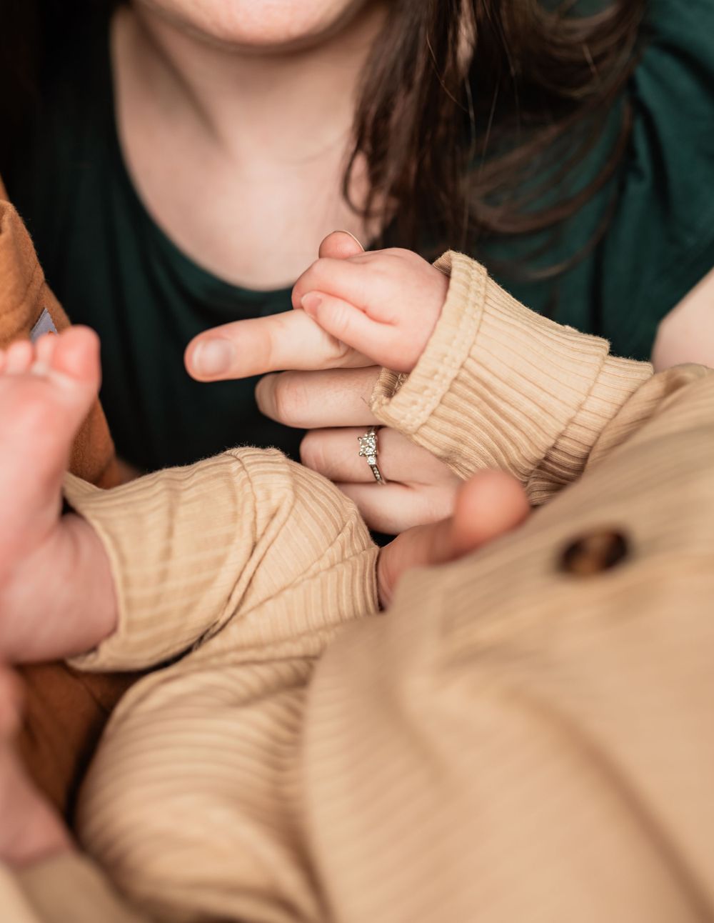 Close-up of tiny baby fingers grasping while wearing a beige knit outfit.