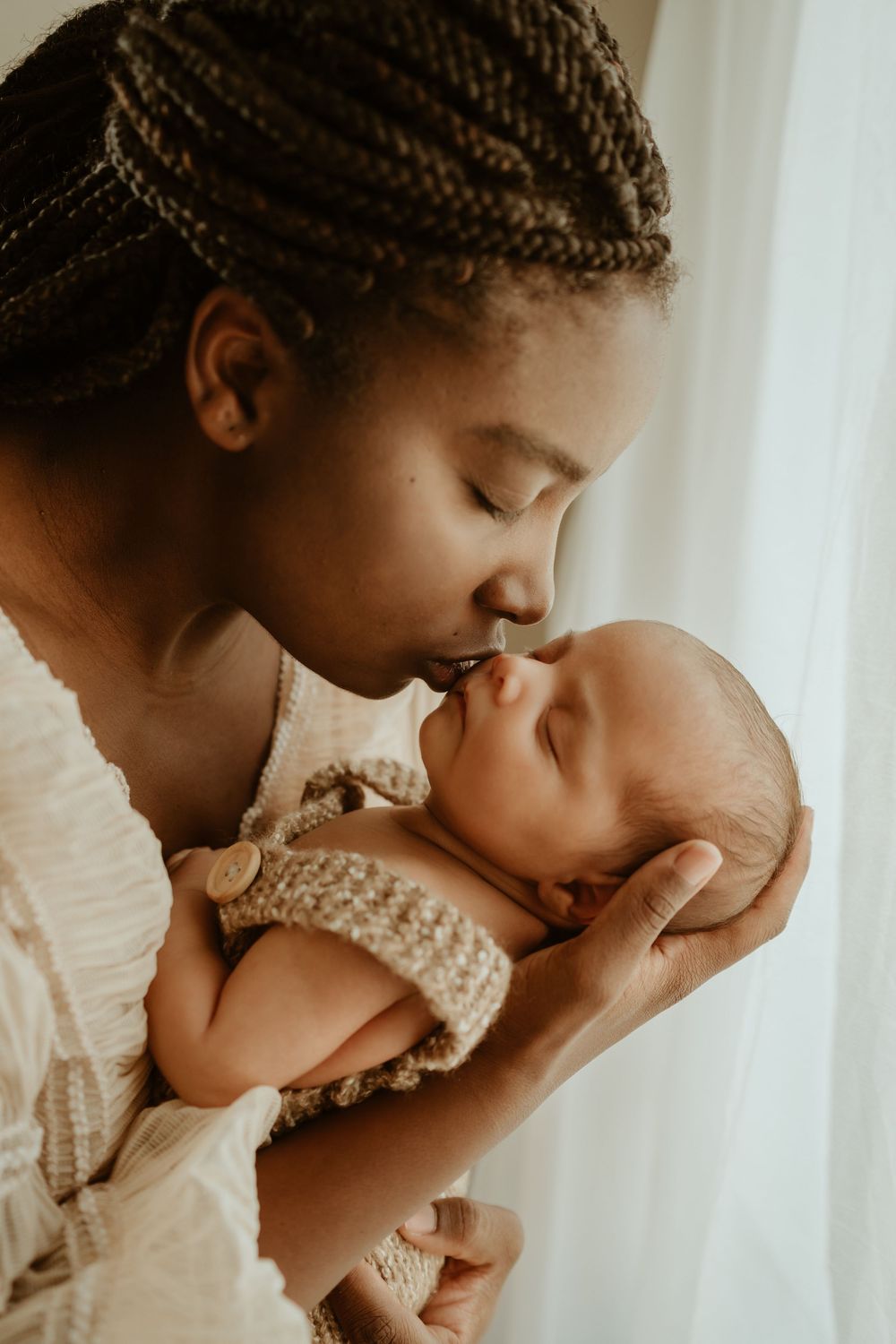 Tender series of intimate newborn portraits showing gentle kisses and bonding moments in soft natural light.