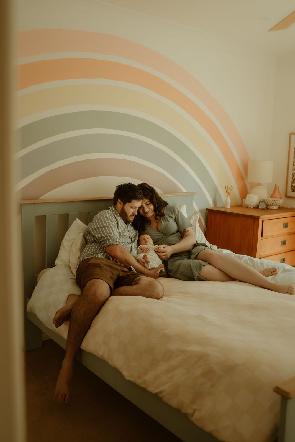 A couple lying together on a white bed in a warm-toned room with curved wall designs.
