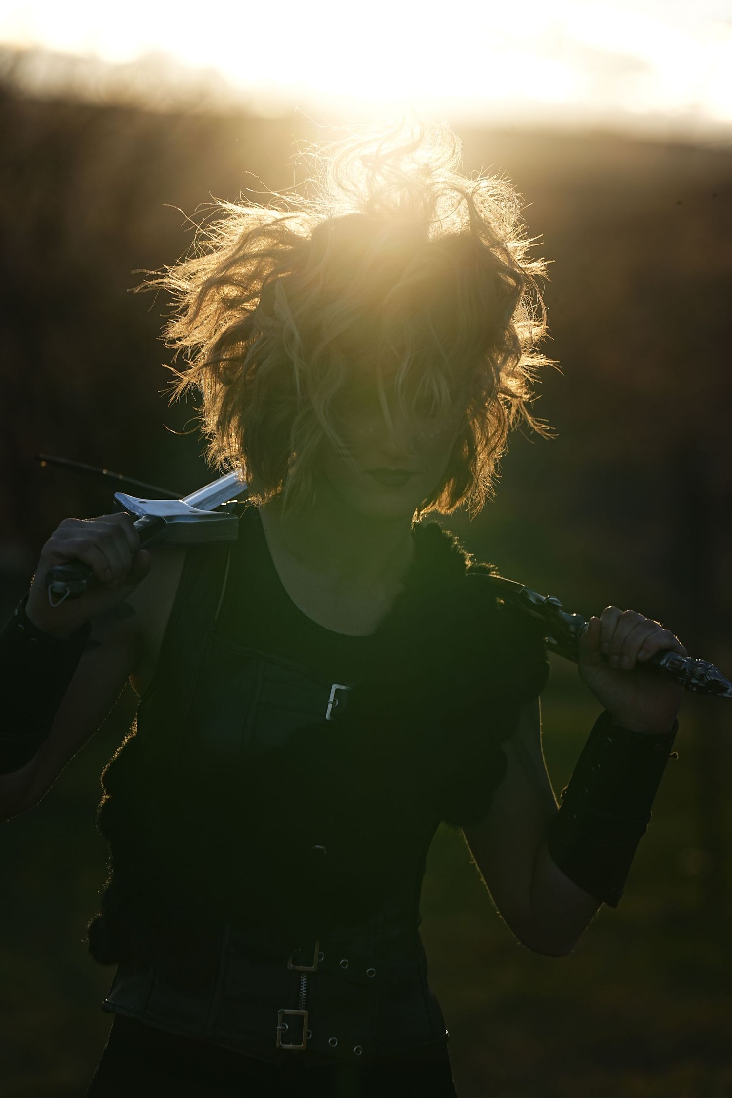 Silhouette of a person with windswept hair backlit by golden sunlight.