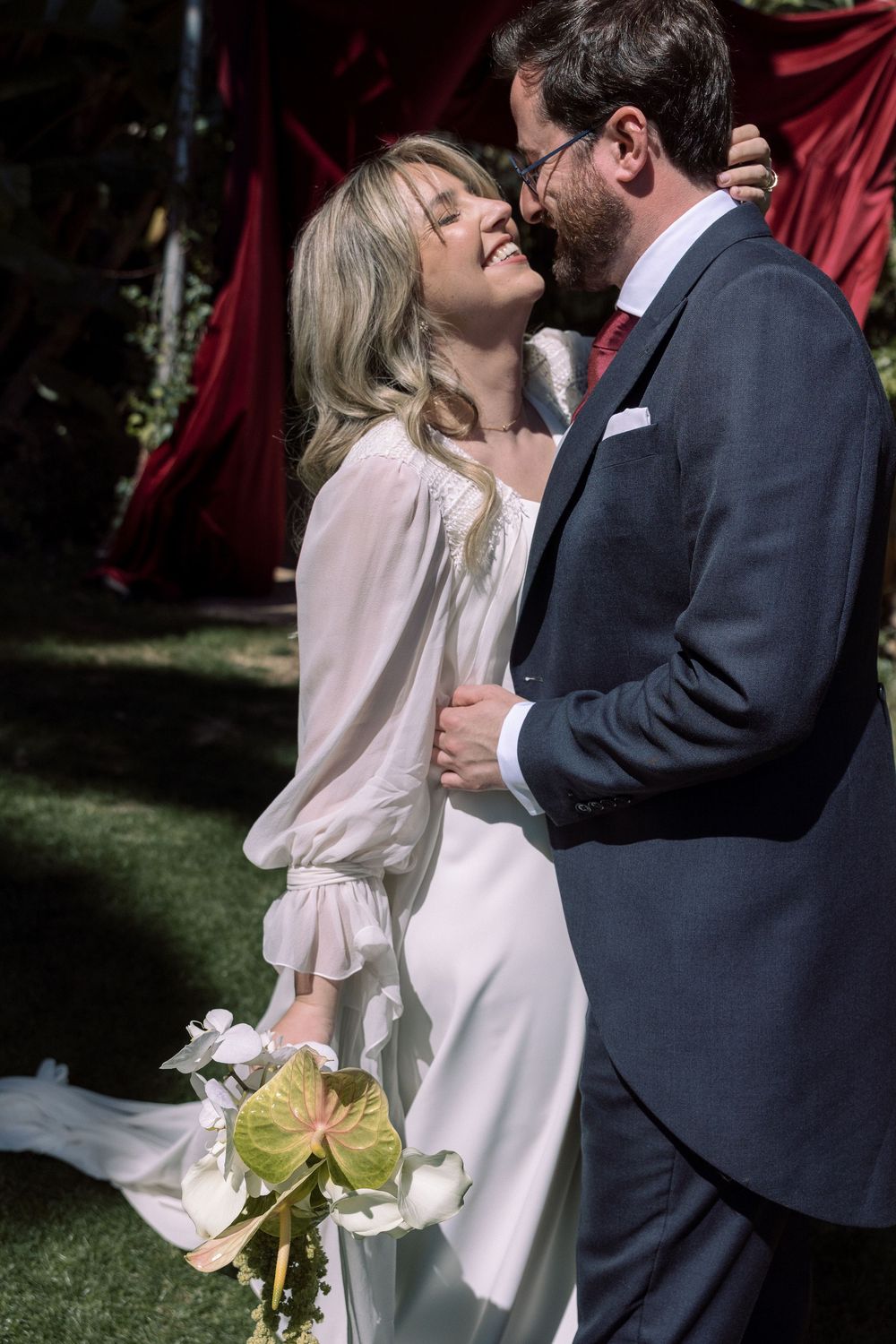 A formal wedding portrait in front of a white backdrop with a castle tower visible in the background.