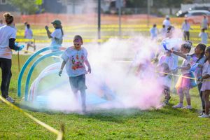 Colorful powder fills the air as participants run through an outdoor course during a color run event.