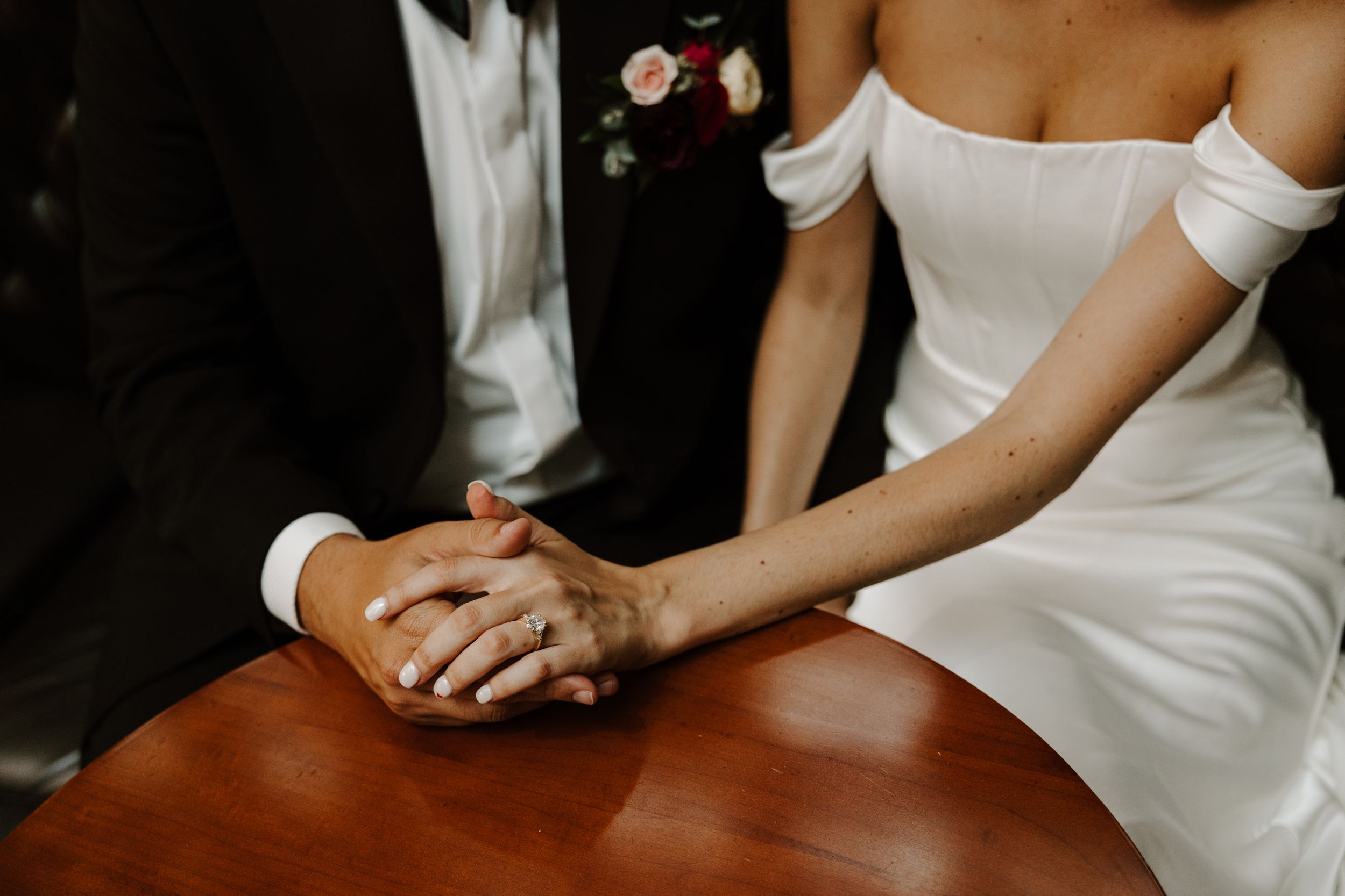 Close-up of couple holding hands across a wooden table.