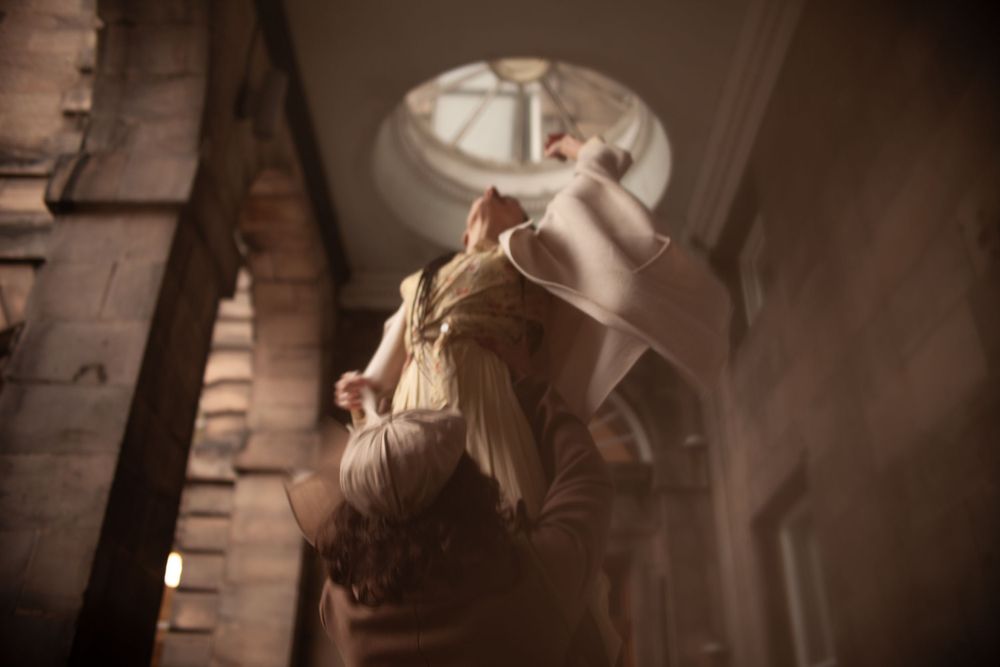 Dramatic dance movement captured in vintage architecture with flowing fabric.