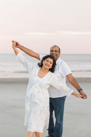 Couple pausing together on the beach at golden hour during a couples anniversary session