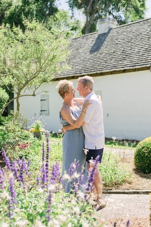 Couple leaning into each other for a natural anniversary portrait in a garden