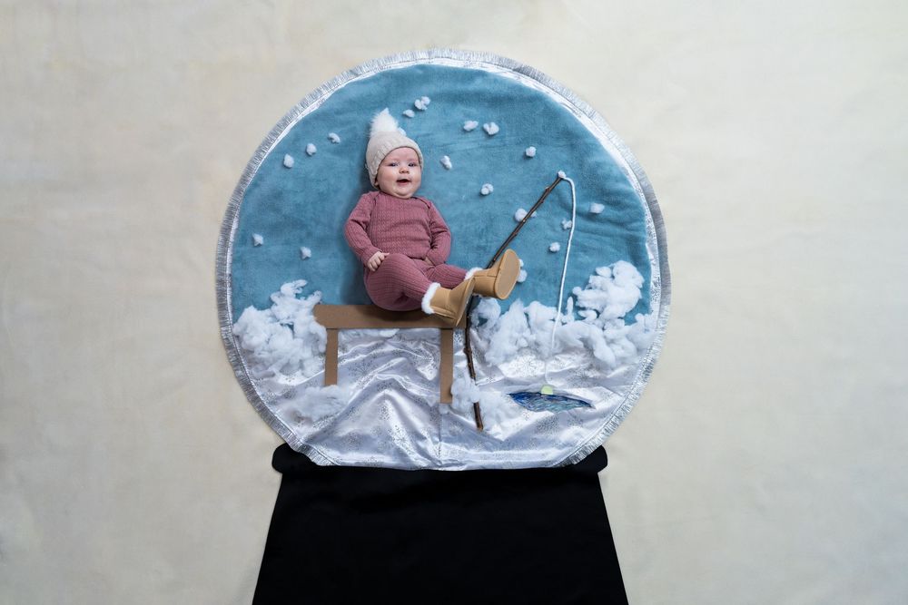 A creative snow globe artwork showing someone on a sled surrounded by a wintery landscape and snowfall.