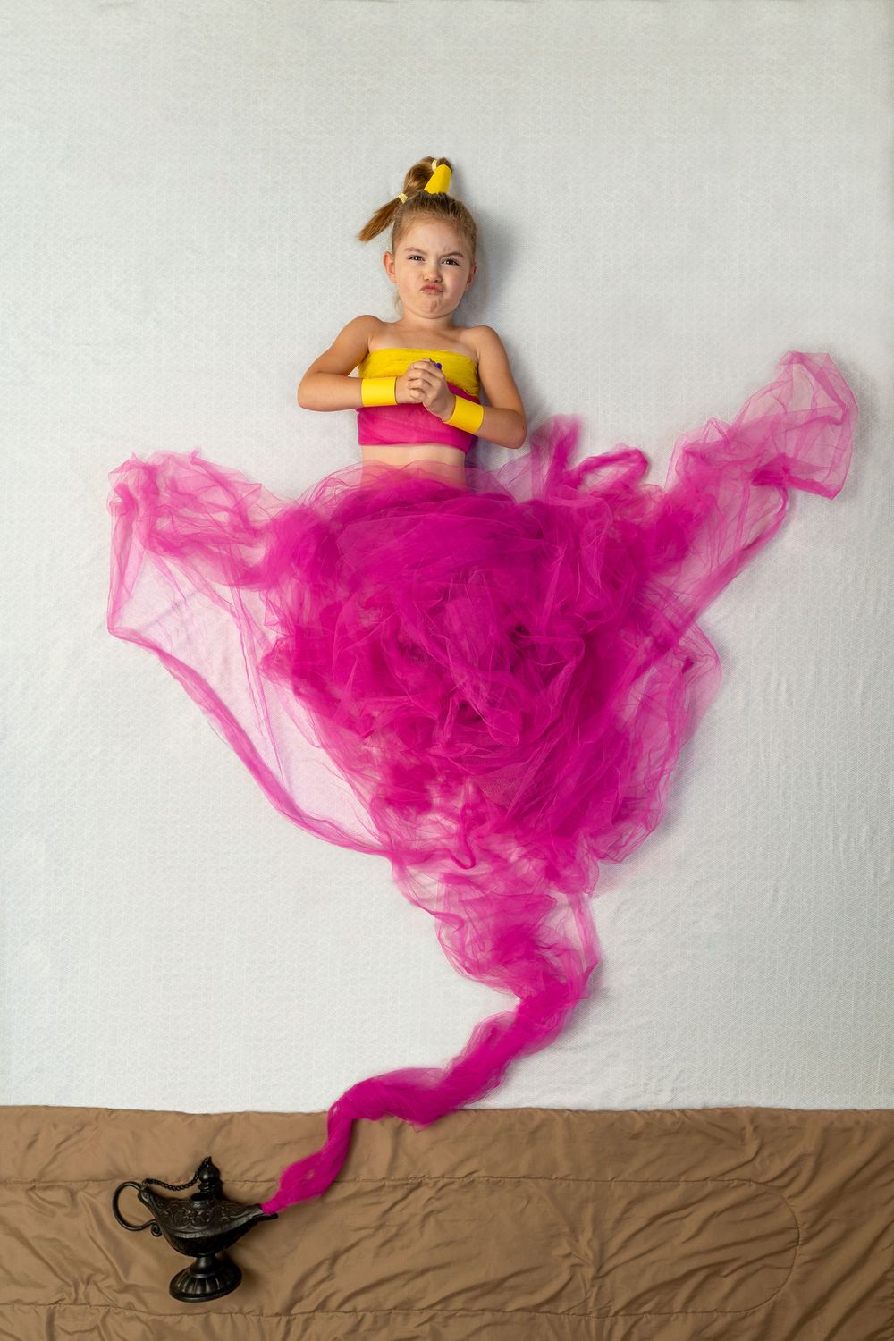 Creative photo of pink smoke emerging from a lamp with yellow accents against white and brown background.