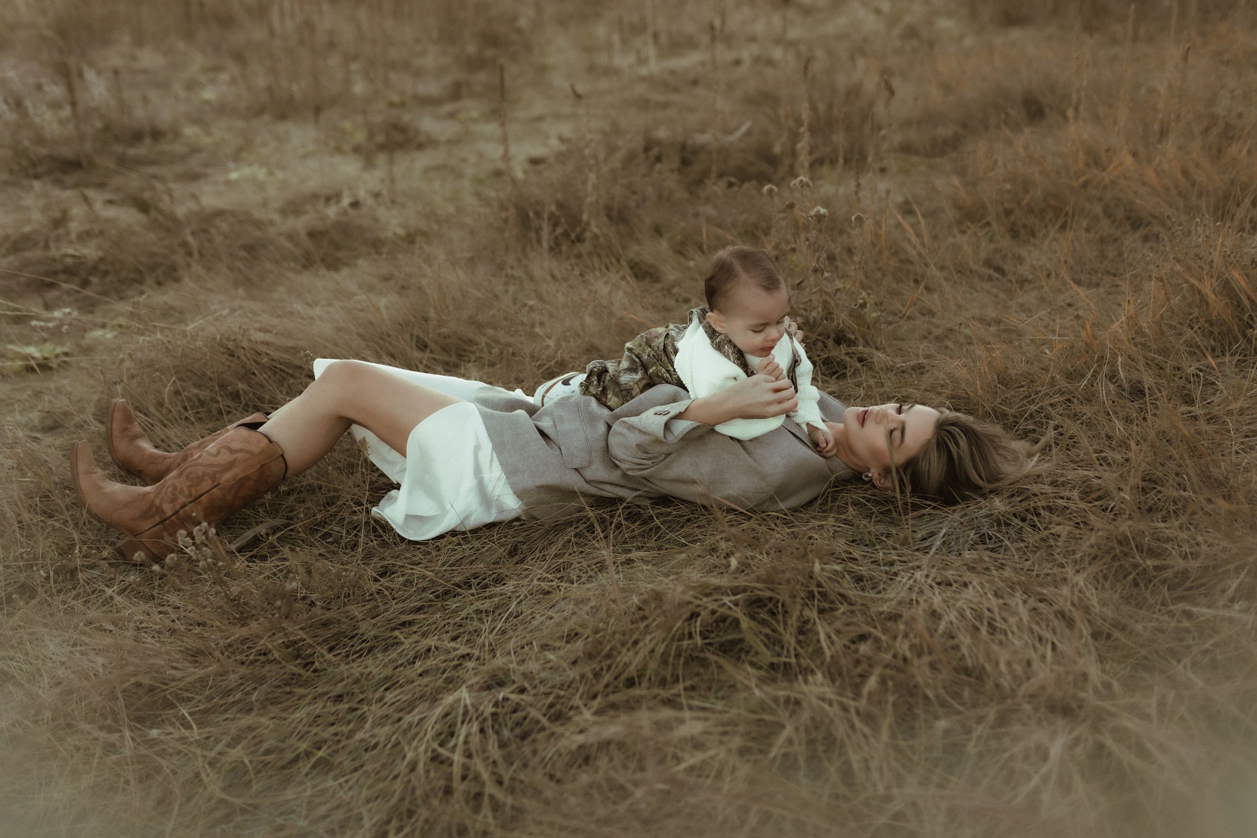 mom and son laying in grass cuddling during a outdoor motherhood session in Boulder Co