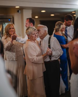 Elegant couples dance together at an indoor wedding reception with warm lighting and formal attire.