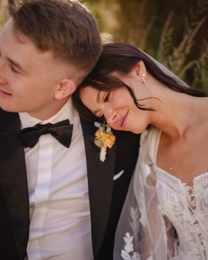 Romantic wedding portrait of couple in formal attire sharing an intimate moment at sunset.