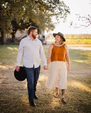 Couple walking through a sun-drenched field during golden hour.