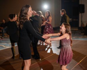 Dancers moving on a dark dance floor under dramatic stage lighting.
