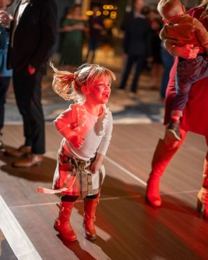 People dancing on a wooden floor illuminated by red stage lighting.