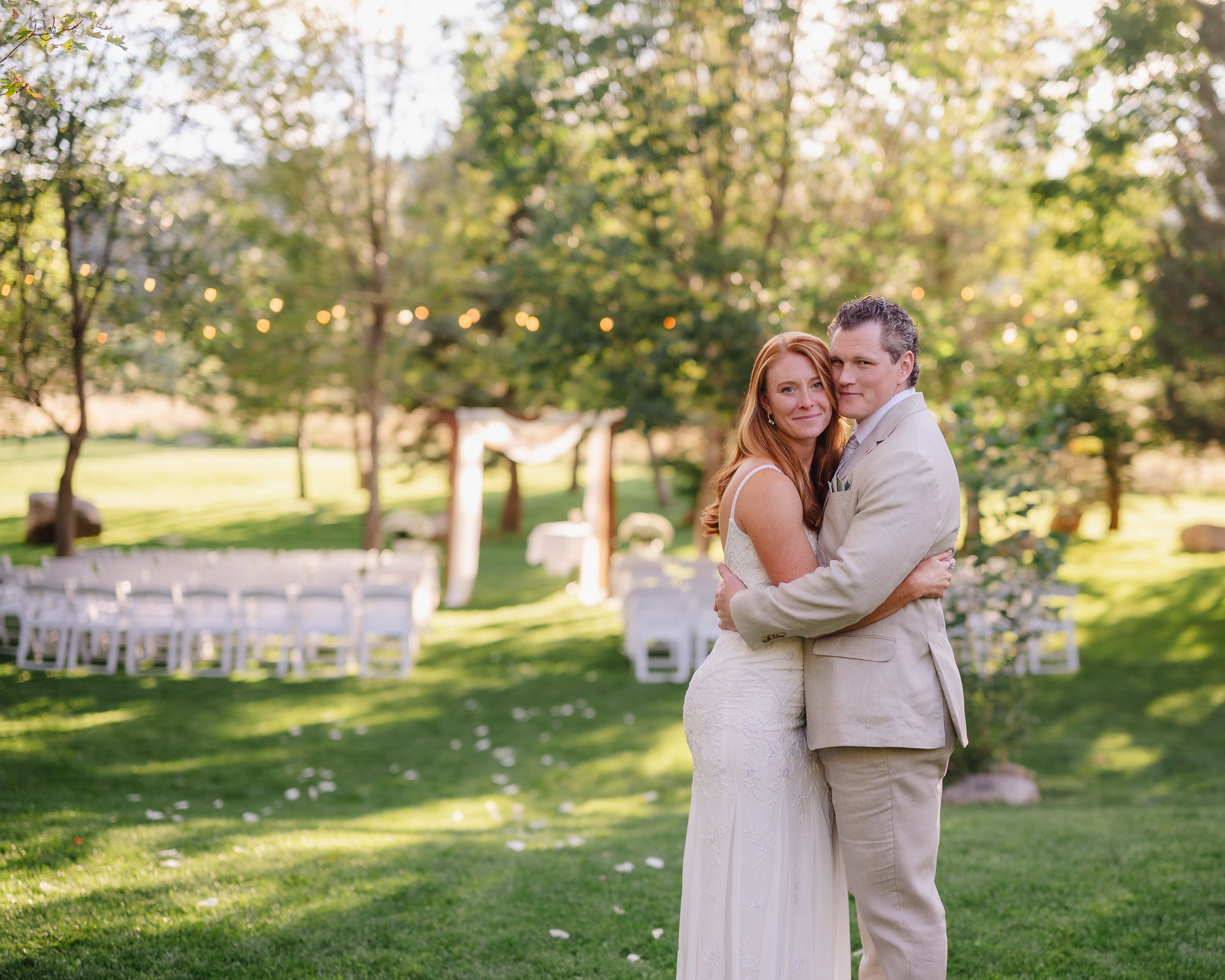 A couple shares intimate moments during their outdoor wedding photoshoot in a sunny garden setting.