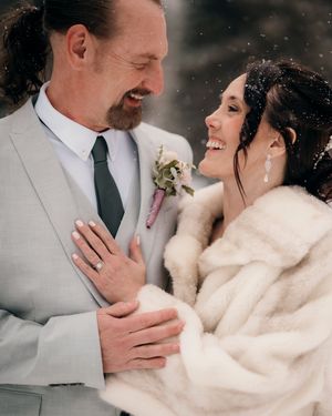 Romantic winter wedding couple embracing in formal attire with fur wrap.