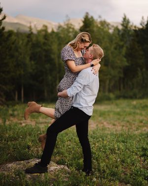 Playful engagement photo session in a grassy field at sunset.