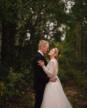 A romantic wedding moment captured in a wooded forest setting.