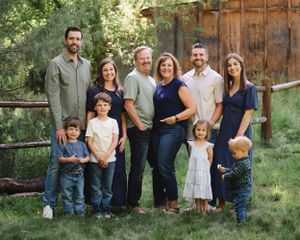 Family portrait session outdoors with rustic wooden backdrop and natural scenery.