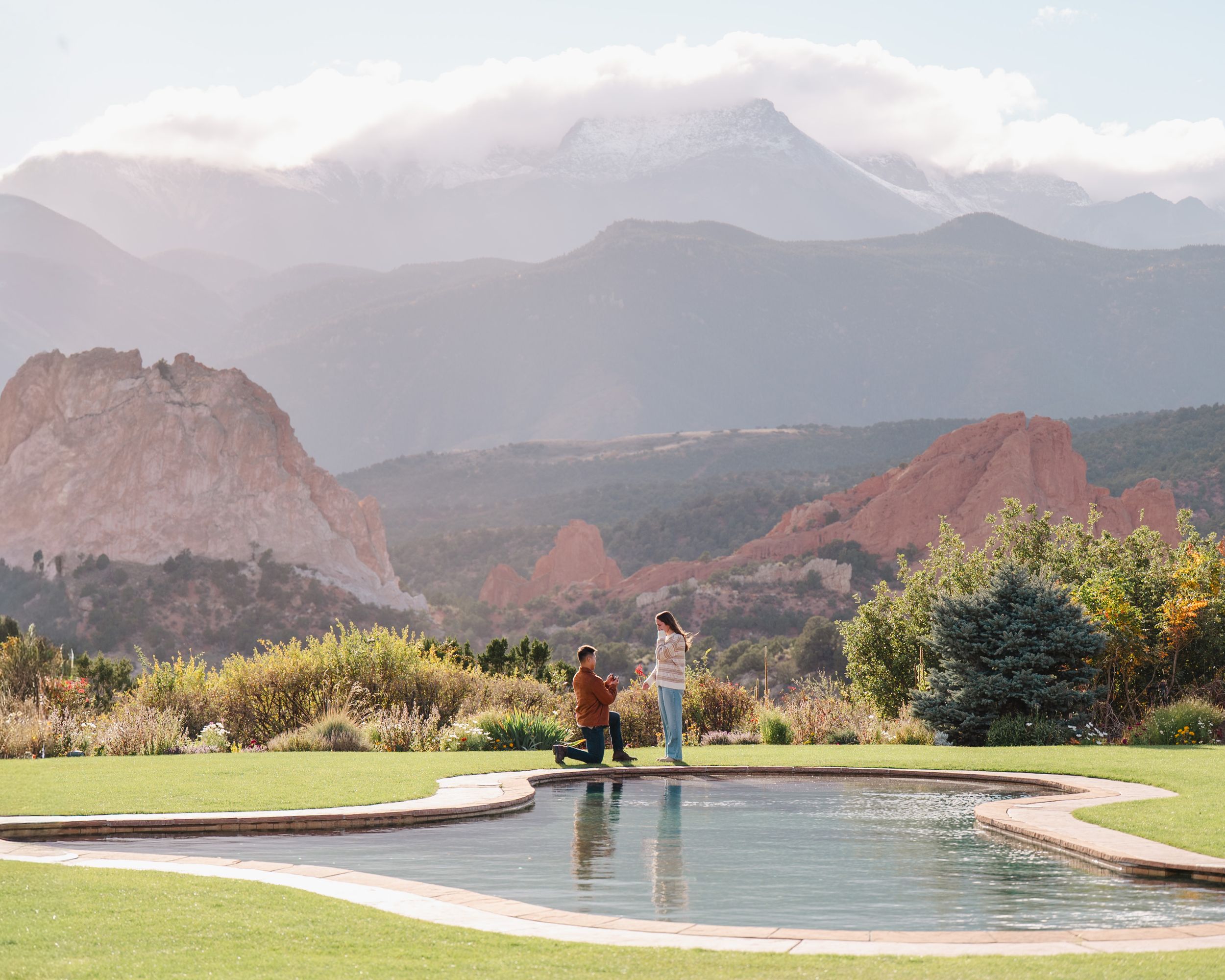 Panoramic view of Garden of the Gods park in Colorado Springs with red rock formations and mountain peaks in background.