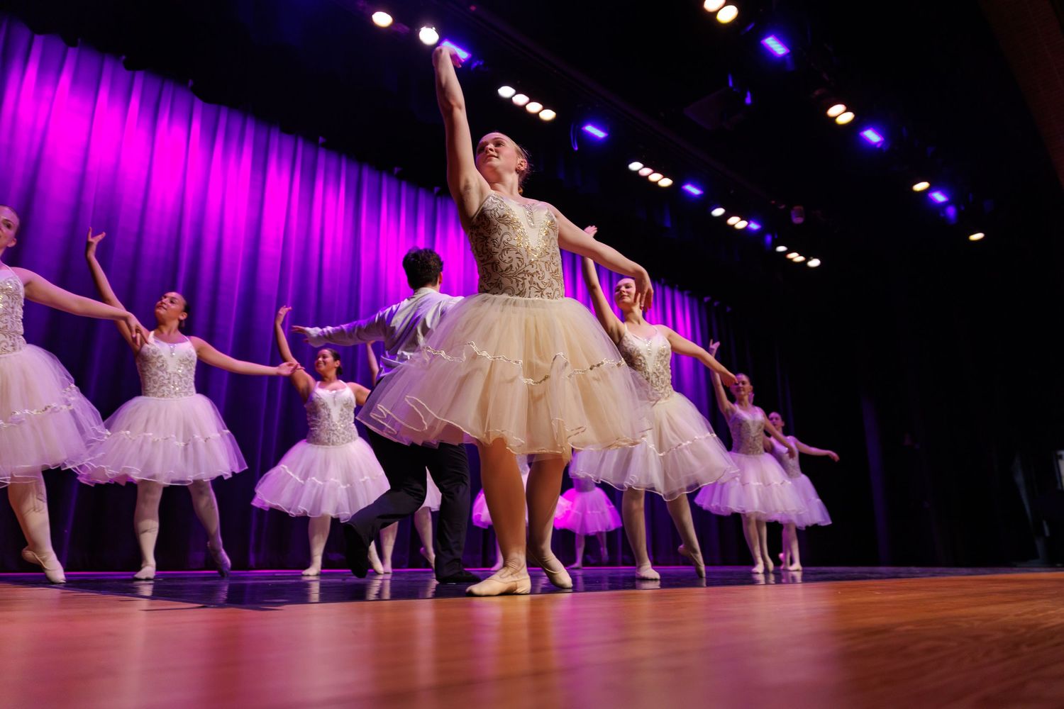 Ballet dancers in point shoes
 perform under dramatic stage lighting.