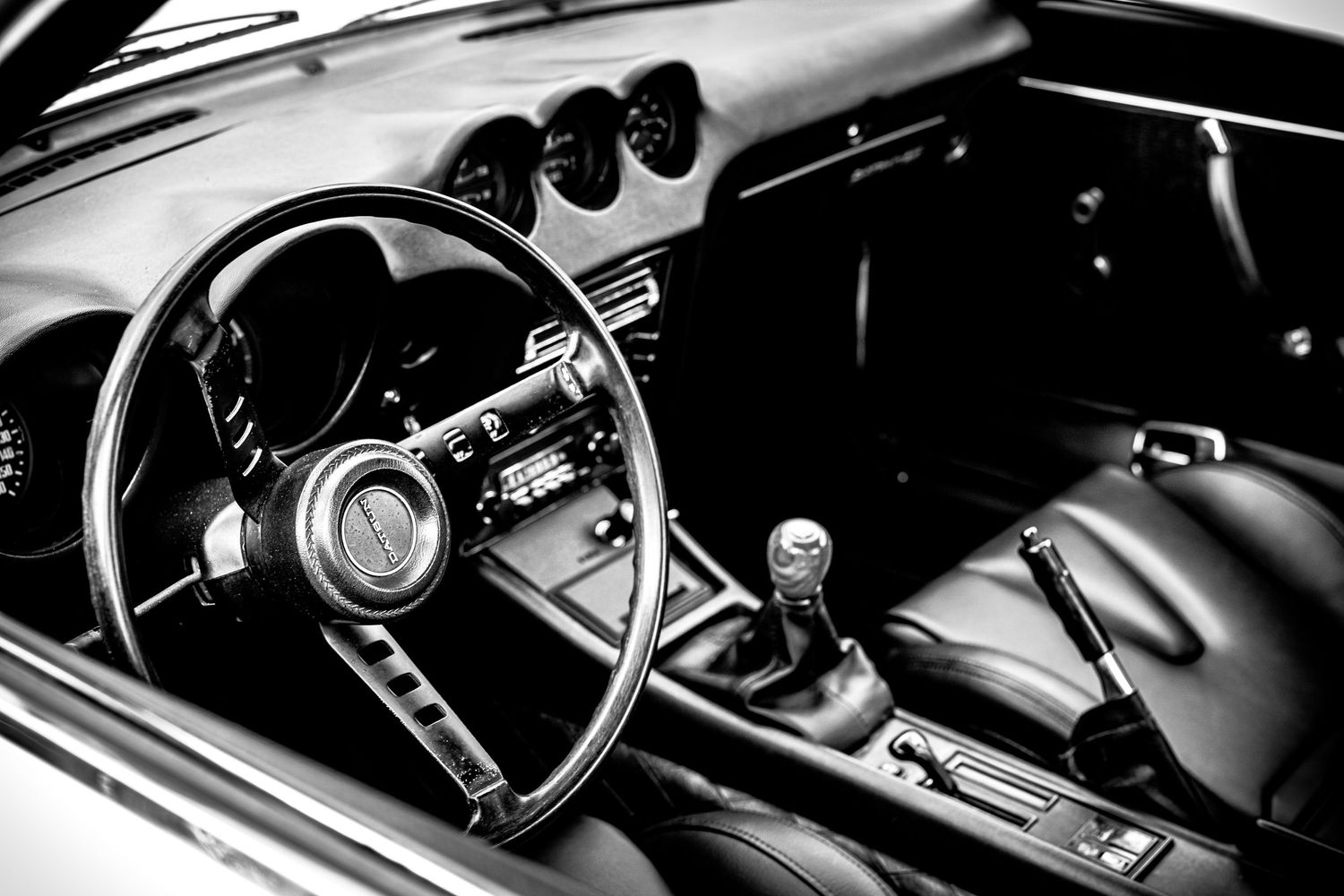 Interior detail shots of classic car dashboard and controls showing vintage steering wheel and gauges in black and white.