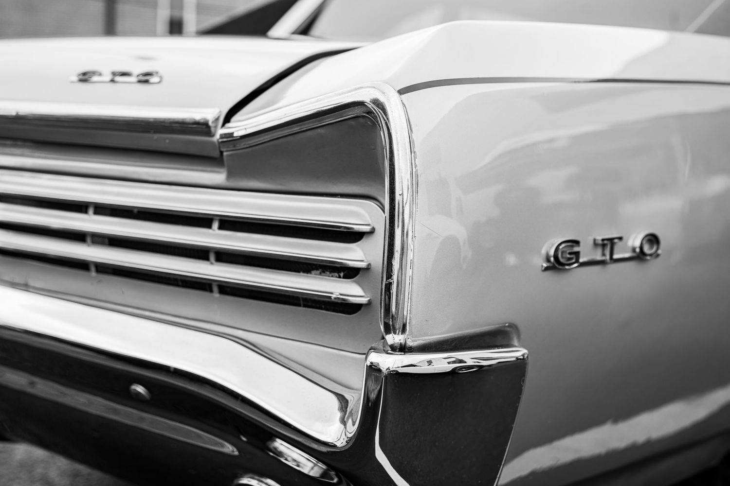 Black and white close-up detail of a vintage GTO car showing chrome grille and badging.