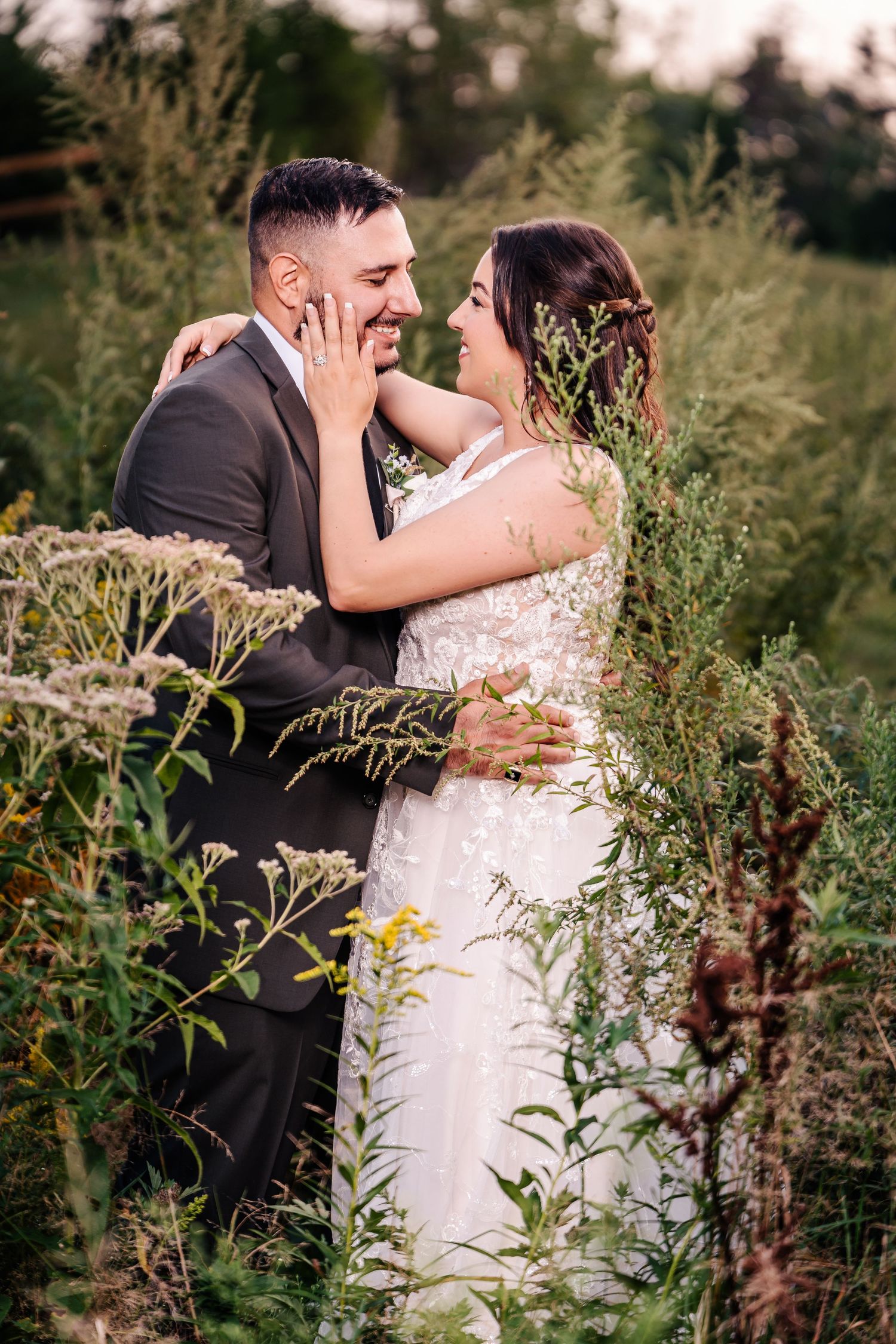 Romantic moment between newlyweds surrounded by wildflowers during golden hour photography session.