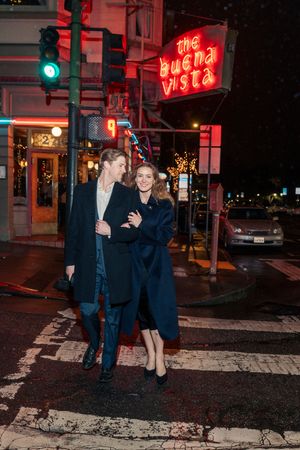 Couple walking arm in arm at night near The Buena Vista cafe in San Francisco.