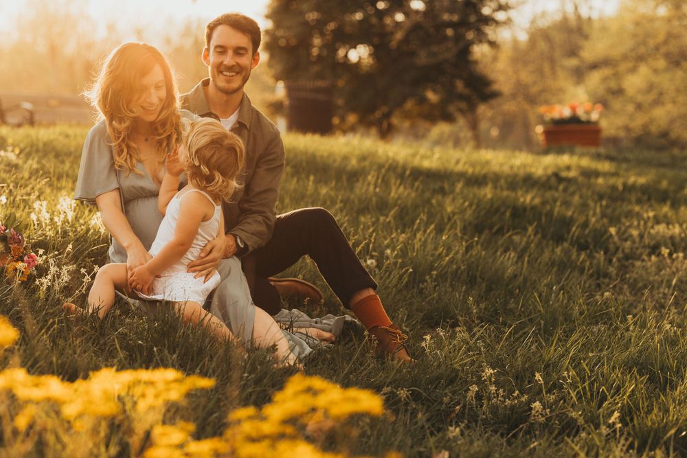 Family sits together in golden meadow during sunset photo session. Annapolis maternity photographer