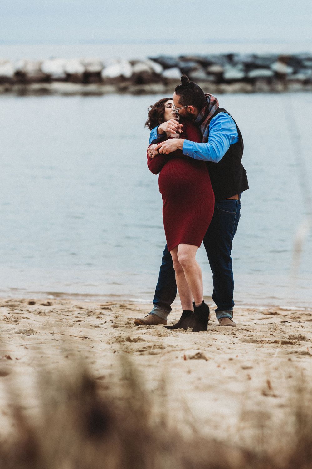 A romantic beach proposal scene with two people embracing on the sandy shore. Annapolis maternity photography
