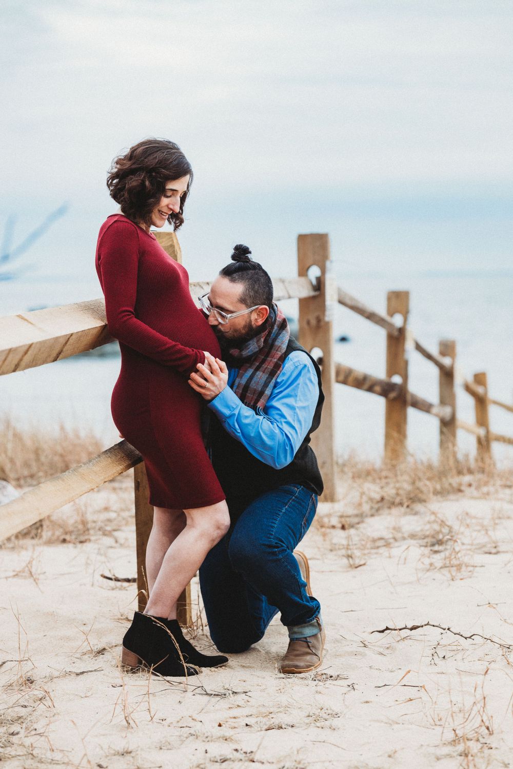 A romantic proposal unfolds on a sandy beach path with wooden fence posts. Annapolis maternity photographer
