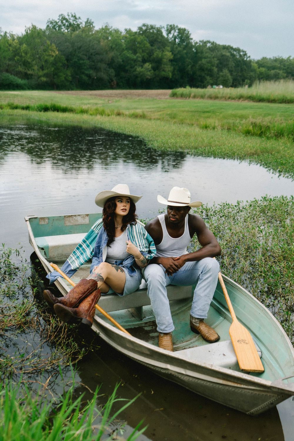 A couple relaxes in a small boat surrounded by marsh grass and water.