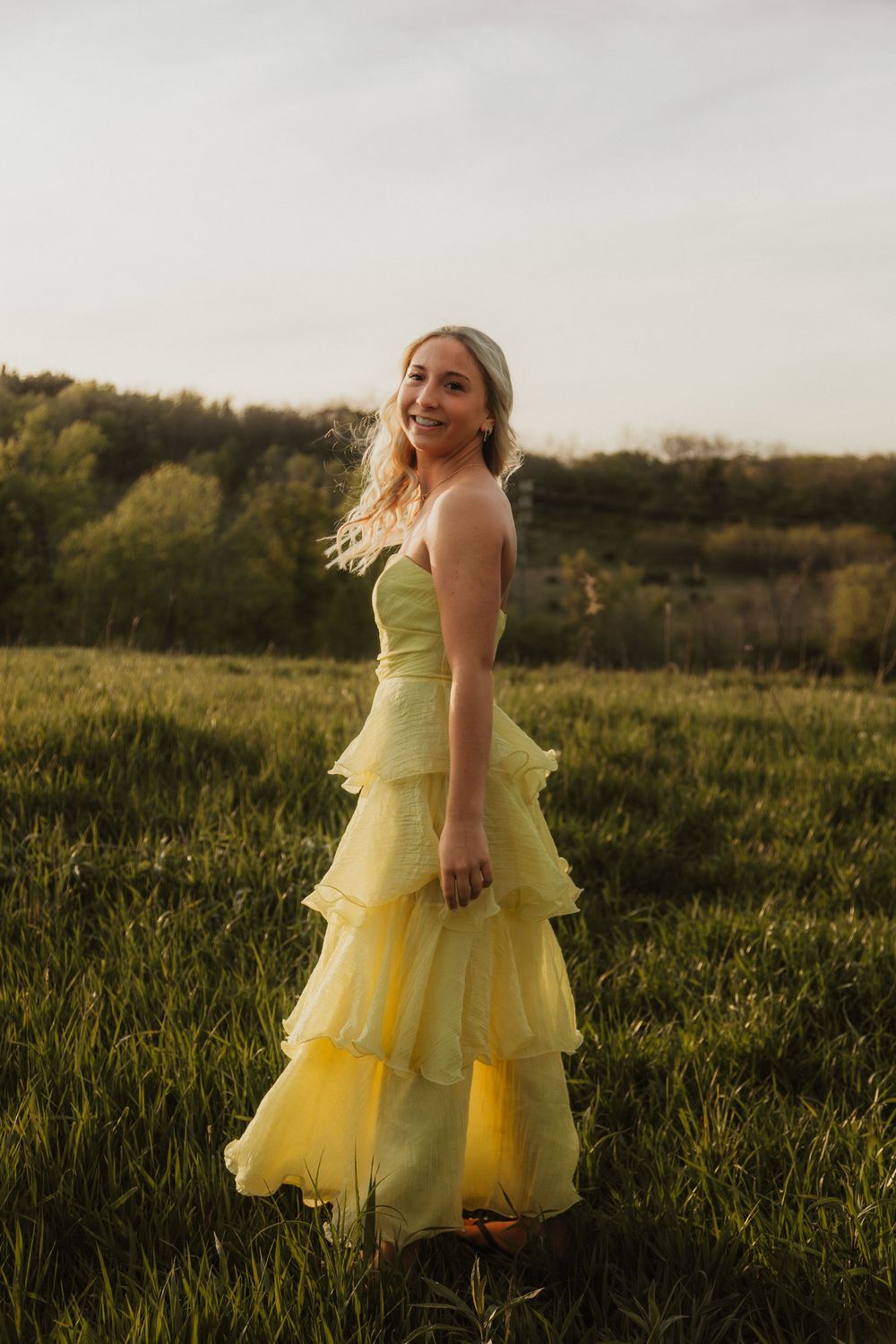 Senior girl spins in a long yellow dress in a field of Prairie grass at Retzer Nature Center in Waukesha, Wisconsin.