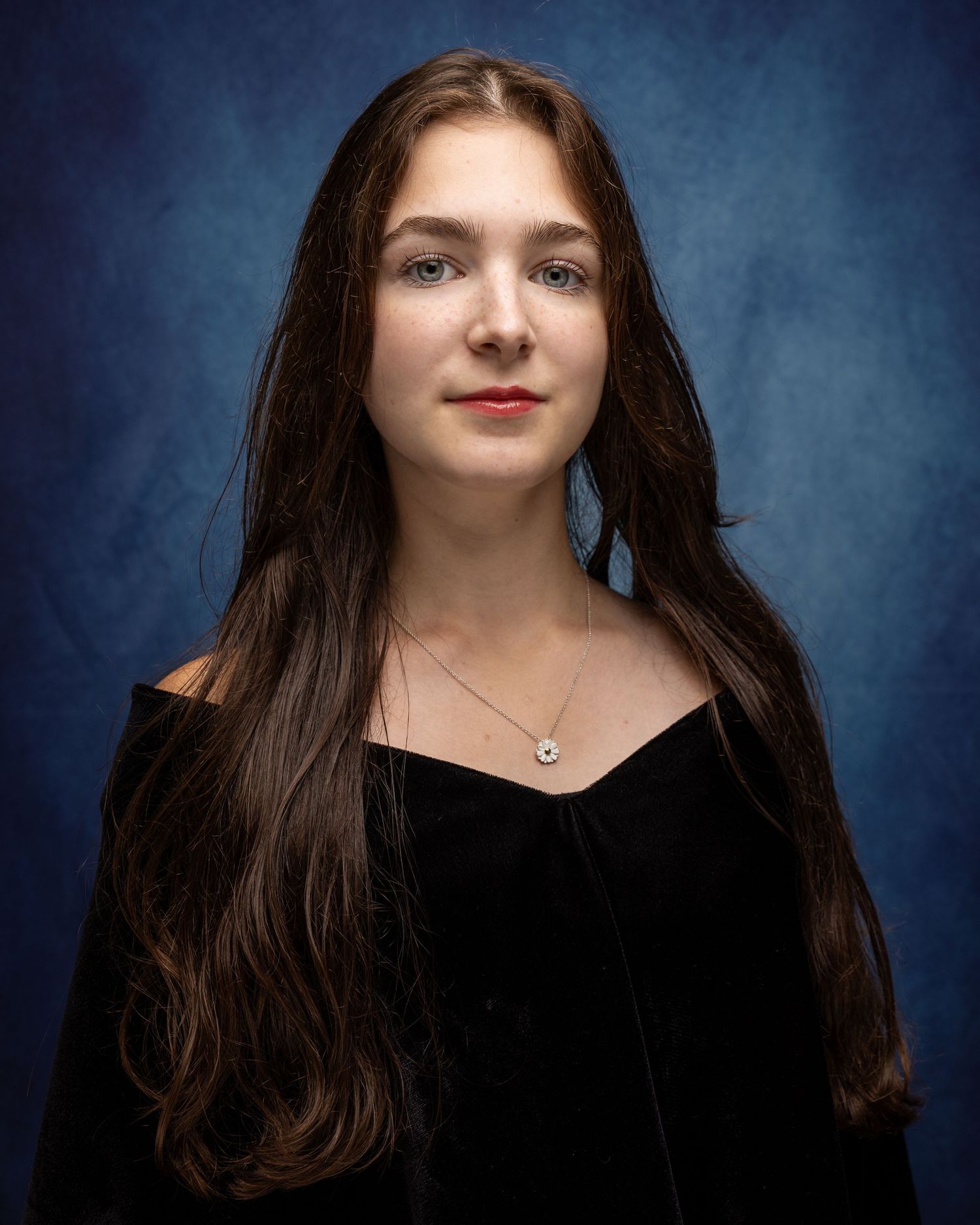 Portrait against blue backdrop showing dramatic lighting and dark hair.