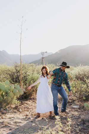 A playful desert photoshoot with mountains and cacti in the background.