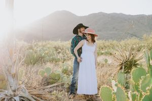 Romantic desert photo session with mountains and native plants at sunset.
