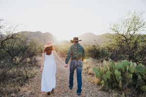 Desert engagement photography with mountains and cactus in golden light.