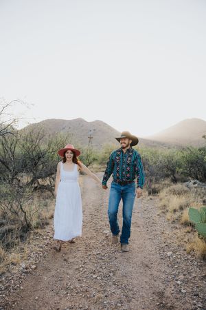 A romantic stroll along a desert path with mountains and cacti creating a scenic backdrop.