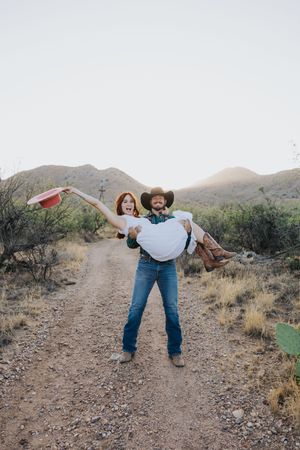 A joyful moment captured as a couple plays and dances on a desert trail.